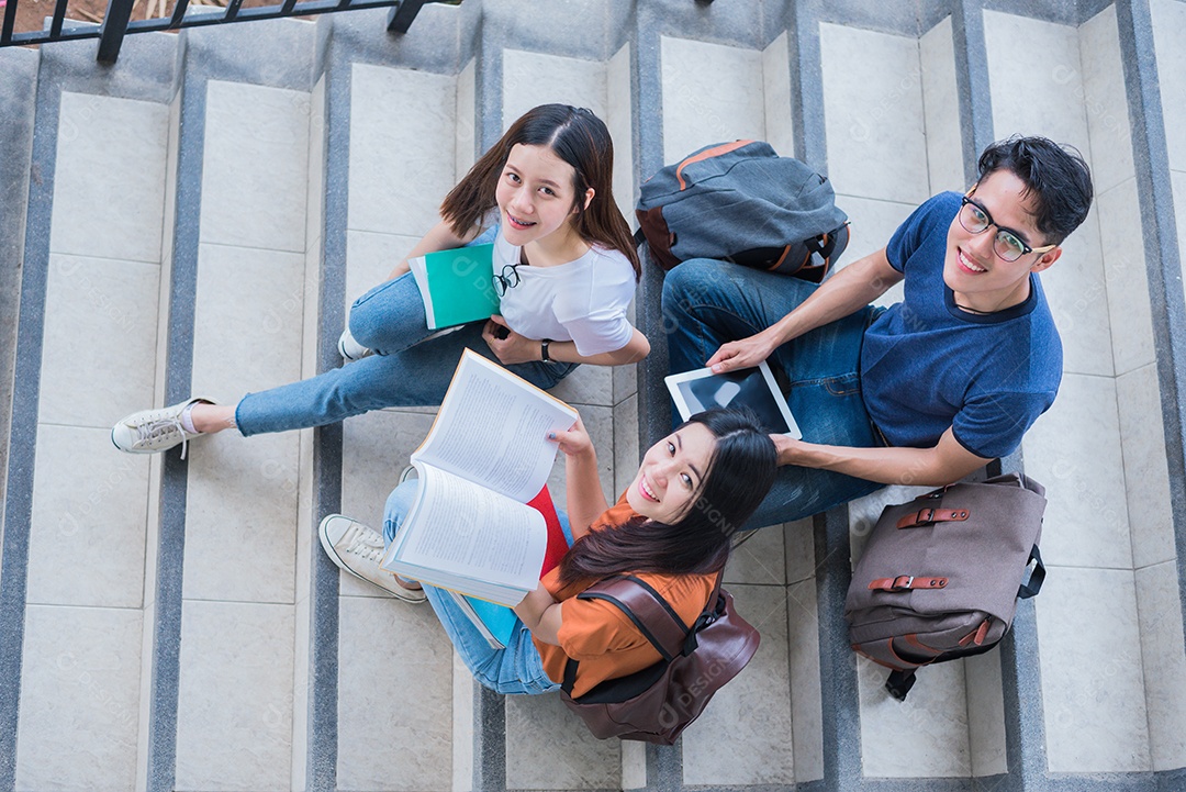 Grupo de estudantes universitários asiáticos usando tablet e celular.
