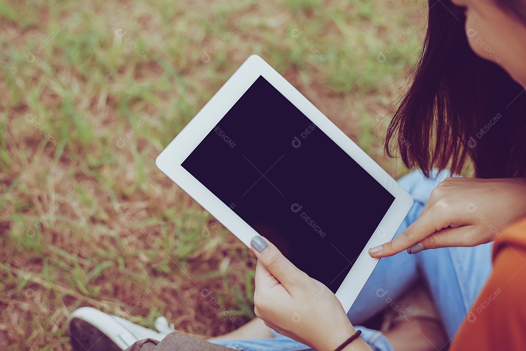 Mulher asiática de beleza usando tablet no parque. Pessoas e Tecnologia.