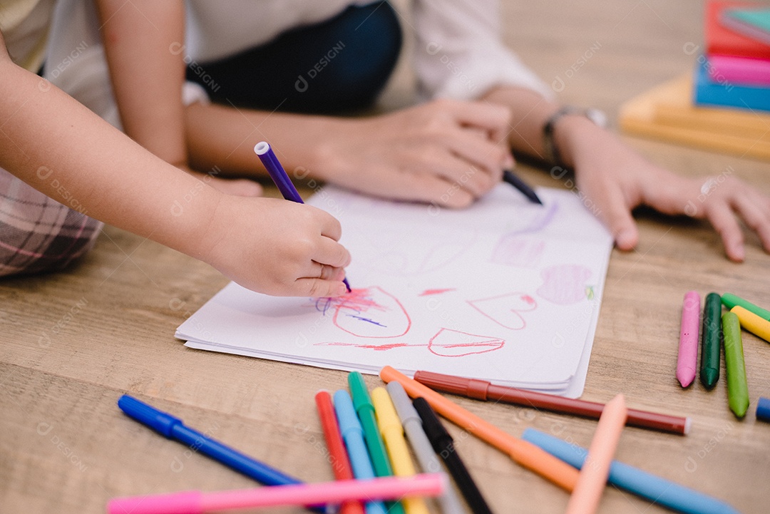 Mãos fechadas da mãe ensinando crianças a desenhar carto.