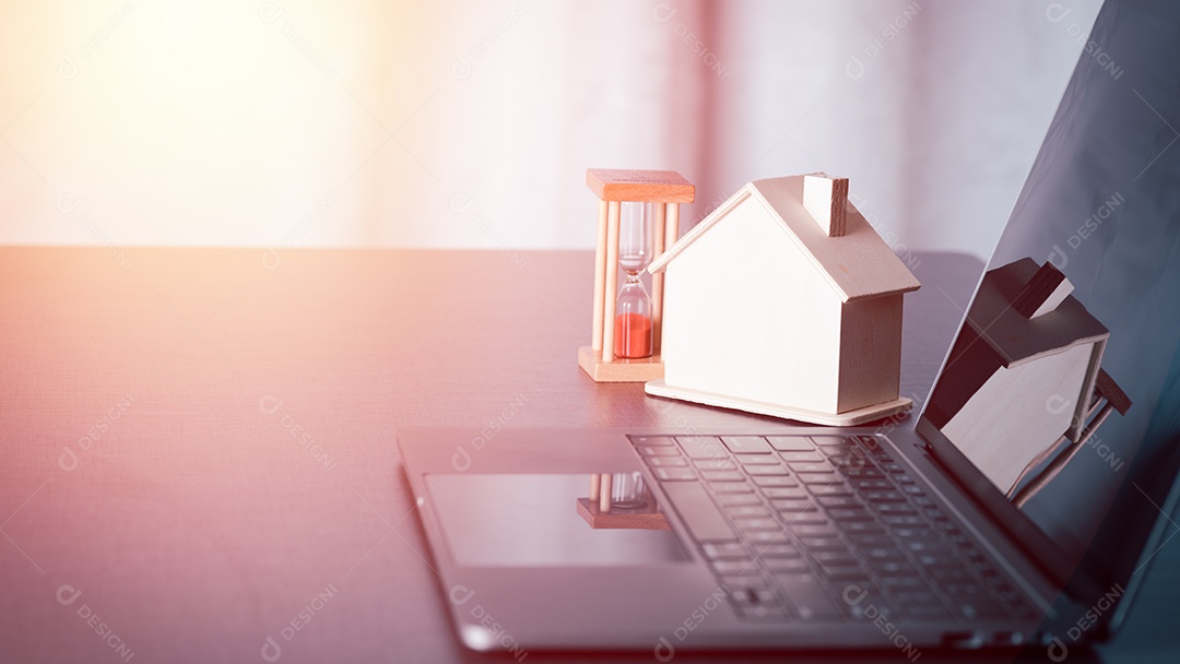 Uma casa modelo e uma ampulheta são colocadas na mesa ao lado