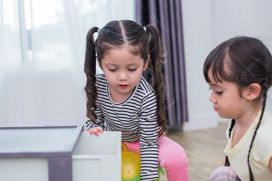 Duas meninas jogando pequenas bolas de brinquedo em casa juntos.