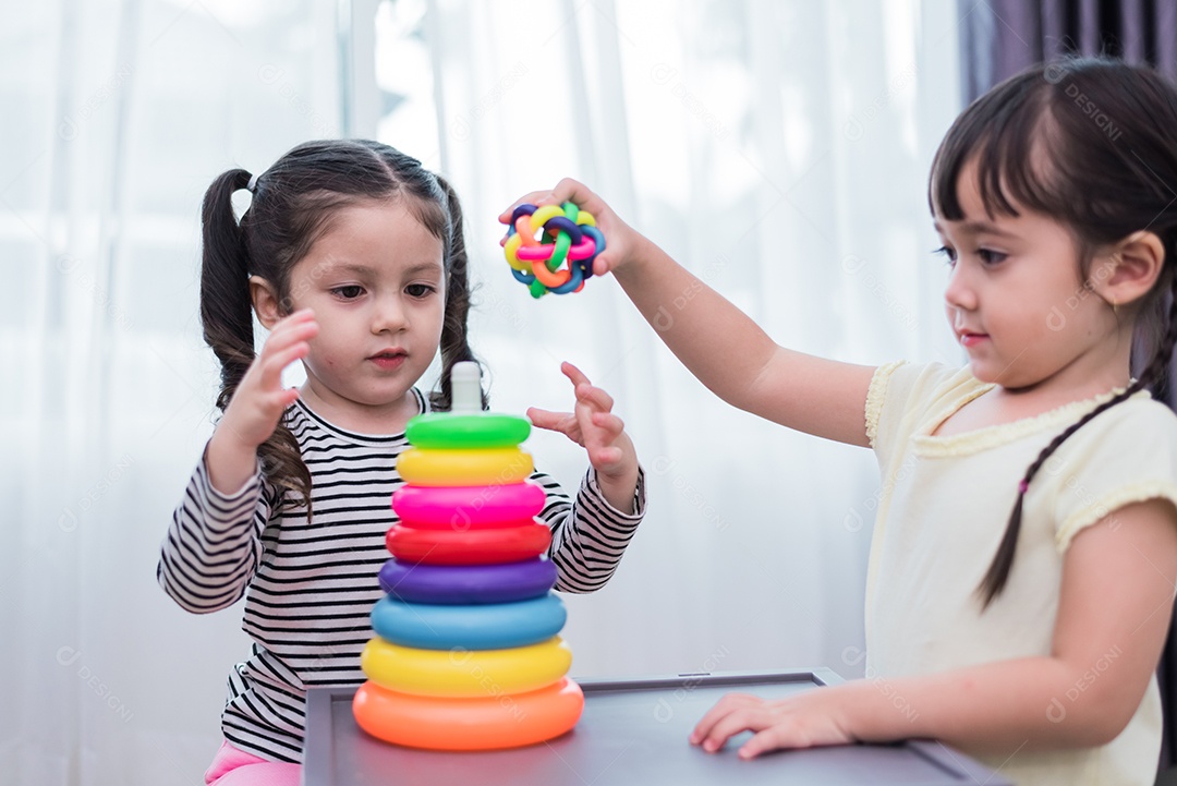 Duas meninas jogando pequenas bolas de brinquedo em casa juntos.