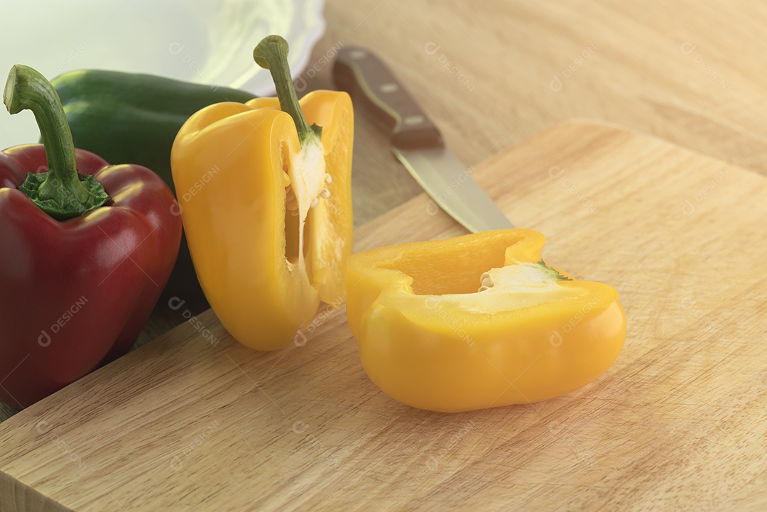 Pimentos doces amarelos, vermelhos e verdes são colocados sobre uma mesa de madeira