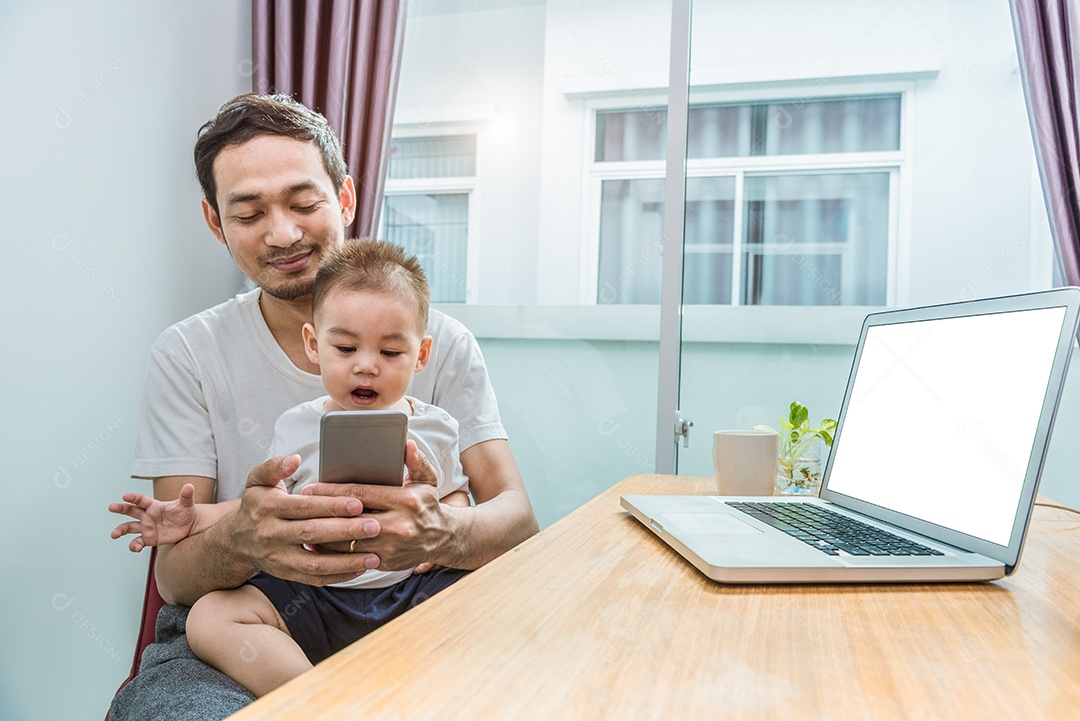 Pai asiático e filho usando telefone inteligente juntos em casa.