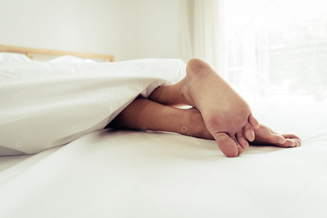 Descalço de humano na cama de manhã. Pessoas solteiras e trabalhadoras.