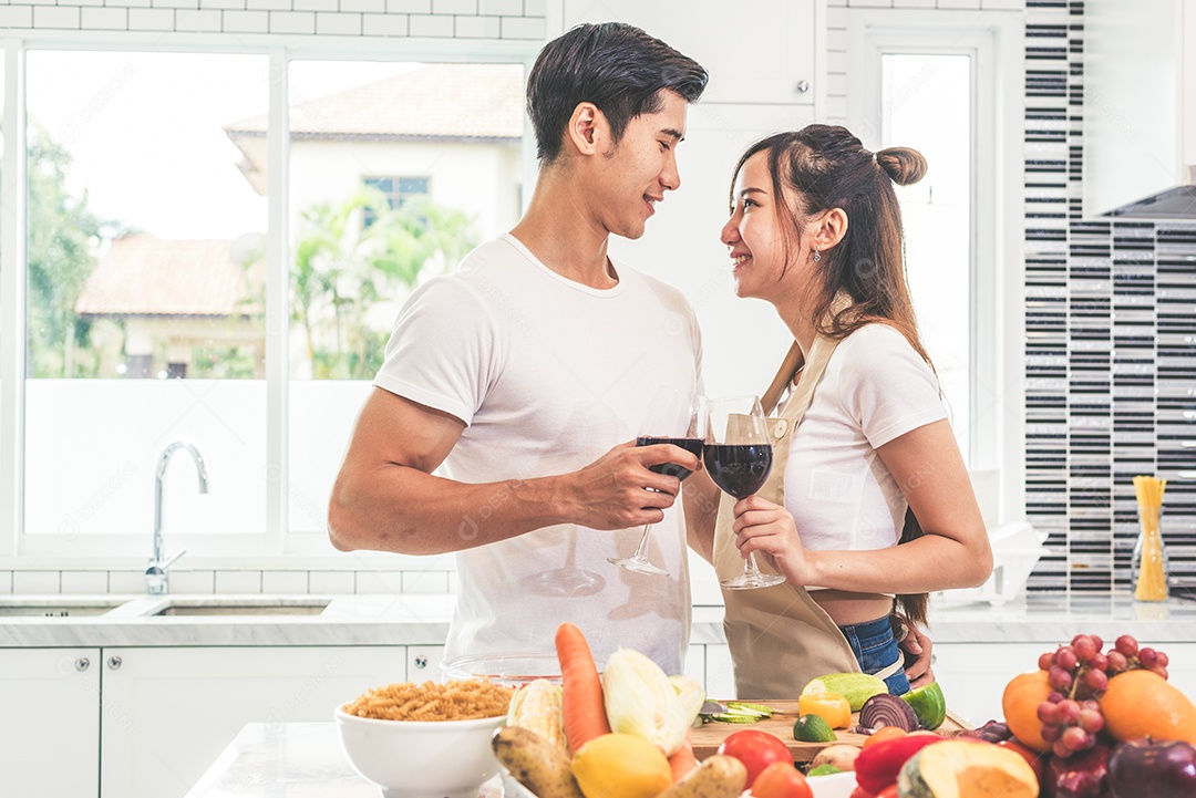 Amantes asiáticos ou casais bebendo vinho na cozinha em casa.