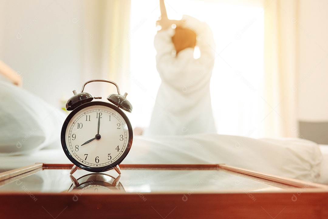 Visão traseira da mulher se alongando pela manhã depois de acordar na cama.