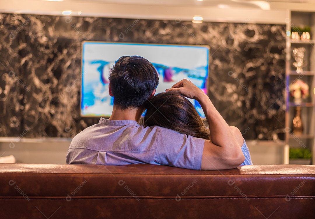 Jovens amantes asiáticos assistindo televisão no sofá. Casais e Relacionamentos.