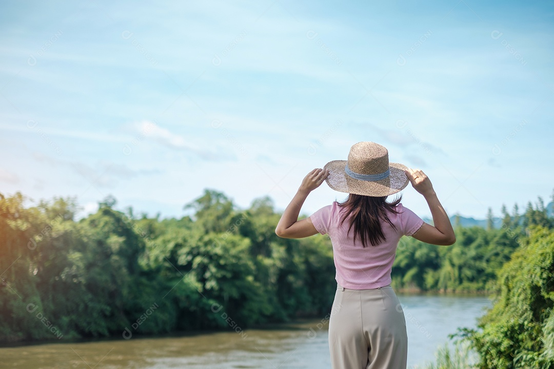 Mulher solo de rosa e chapéu viajando perto do rio. Garota feliz na natureza. popular para atrações turísticas em Kanchanaburi, Tailândia