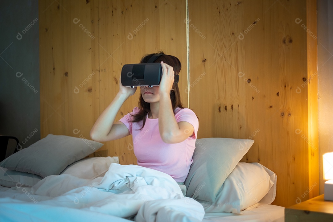 Jovem mulher usando fone de ouvido de realidade virtual na cama. VR, tecnologia digital do futuro, jogo, entretenimento de filmes