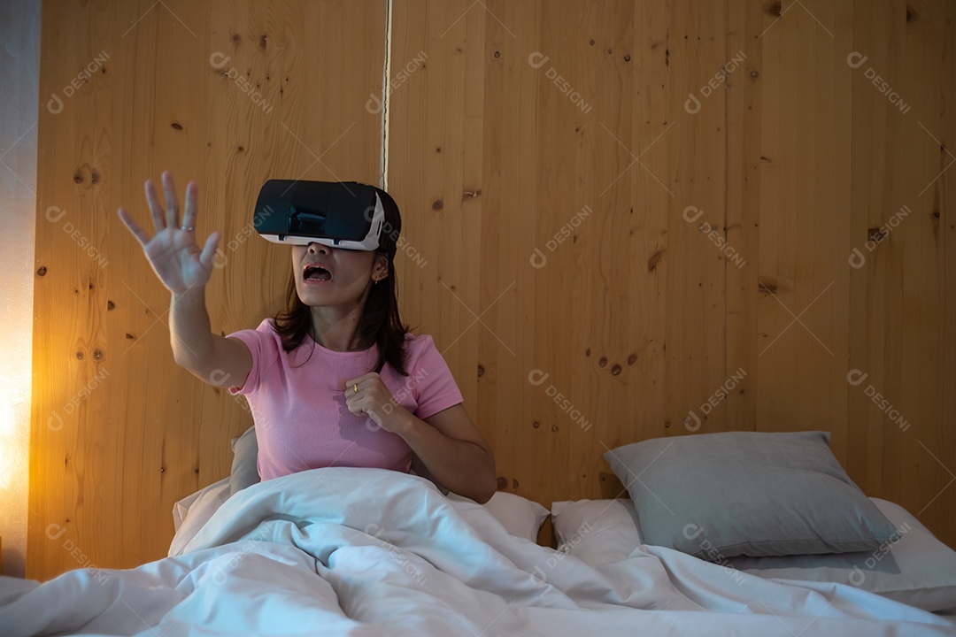 Jovem mulher usando fone de ouvido de realidade virtual na cama. VR, tecnologia digital do futuro, jogo, entretenimento de filmes