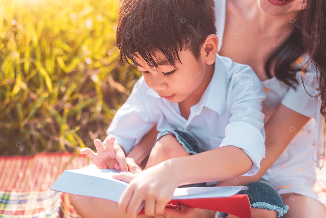 Menino asiático e sua mãe lendo livros de contos de fadas no hidromel.