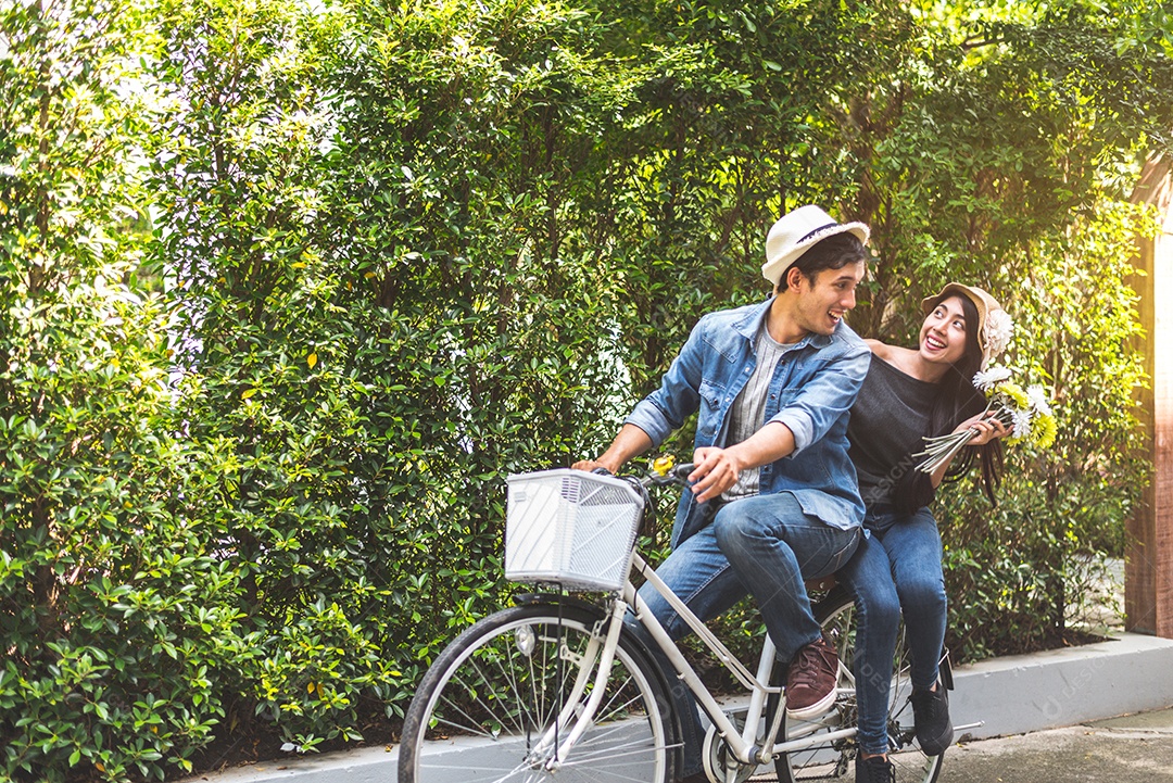 Casal feliz andando de bicicleta juntos no parque de visão romântica.