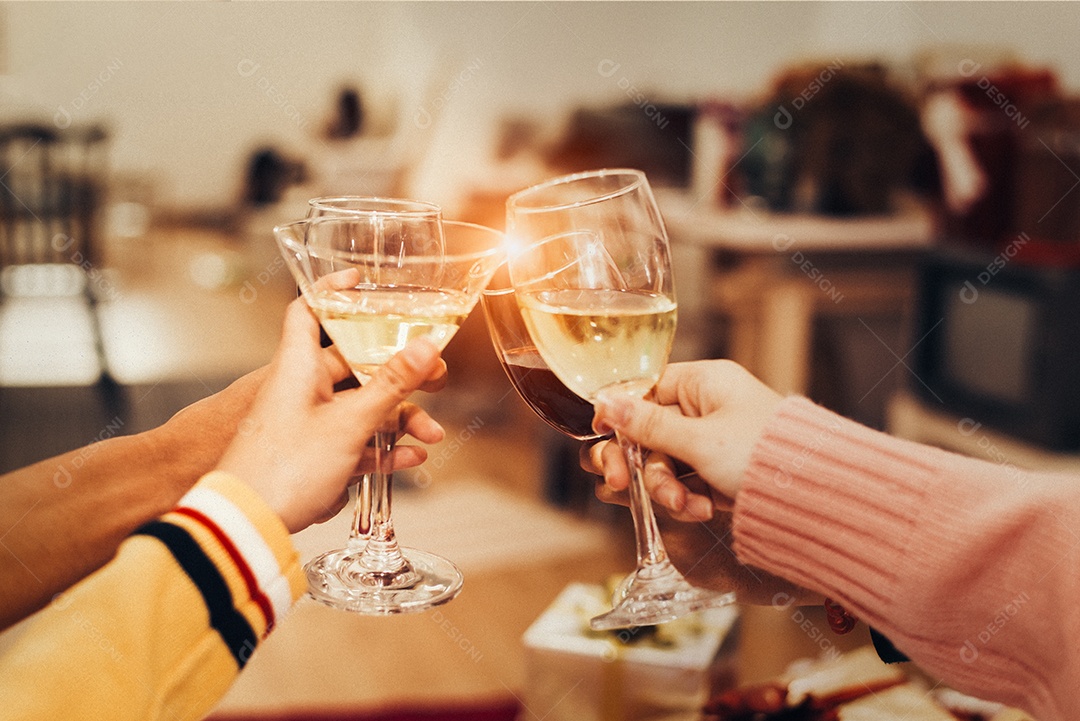 Mãos de pessoas comemorando a festa de ano novo em casa com vinho.