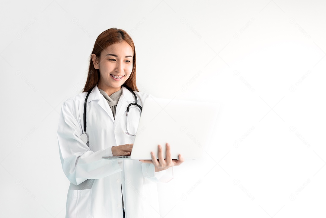 Médica feminina usando laptop com estetoscópio em fundo branco.