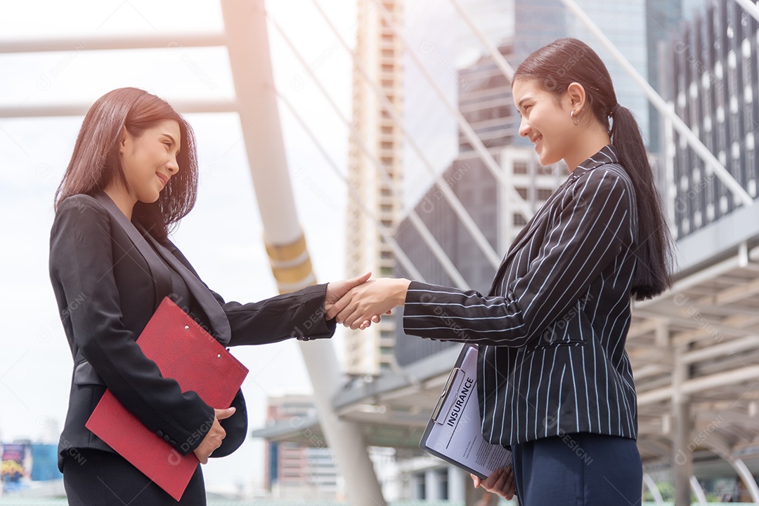 Duas mulheres de negócios apertam a mão ao ar livre com fundo de tráfego, conceito de contrato de negócios e contato.