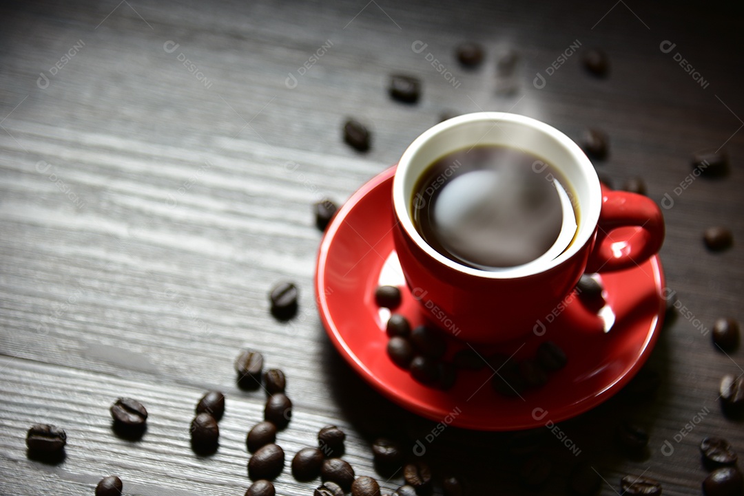 Xícara de café vermelha com fumaça e grãos de café na textura da mesa de madeira,