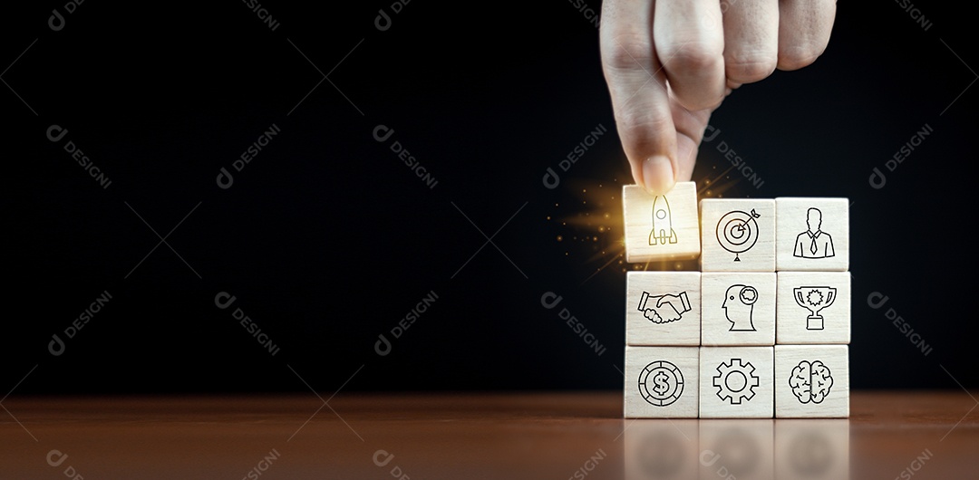 Estratégia de negócios, gestão de negócios ou conceito de sucesso empresarial. Blocos de madeira com ícone de negócios dispostos em forma de escada de pirâmide e um homem está segurando o de cima.