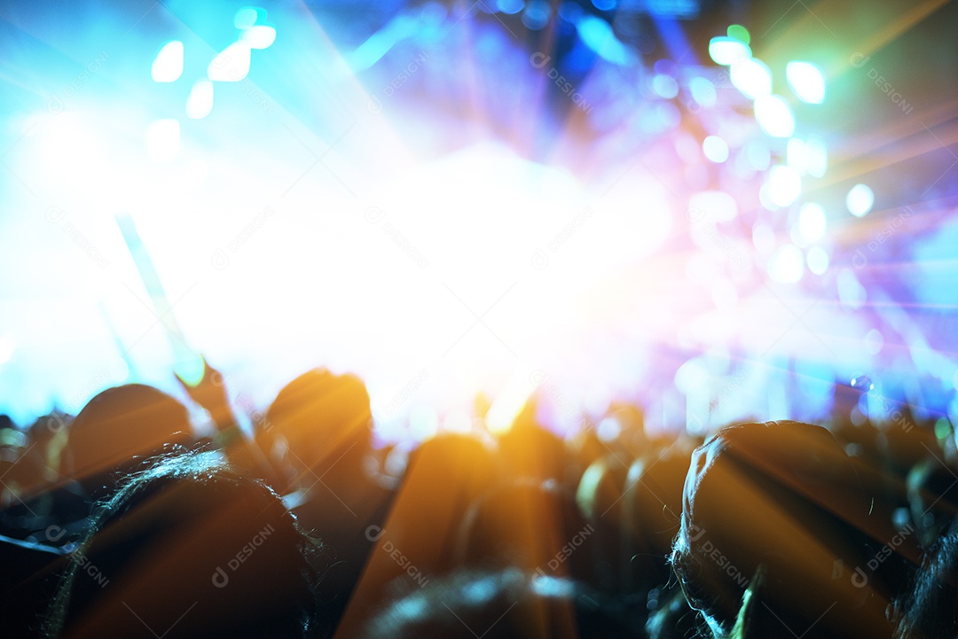 Concerto de rock com pessoas de silhuetas em gesto feliz e passas.