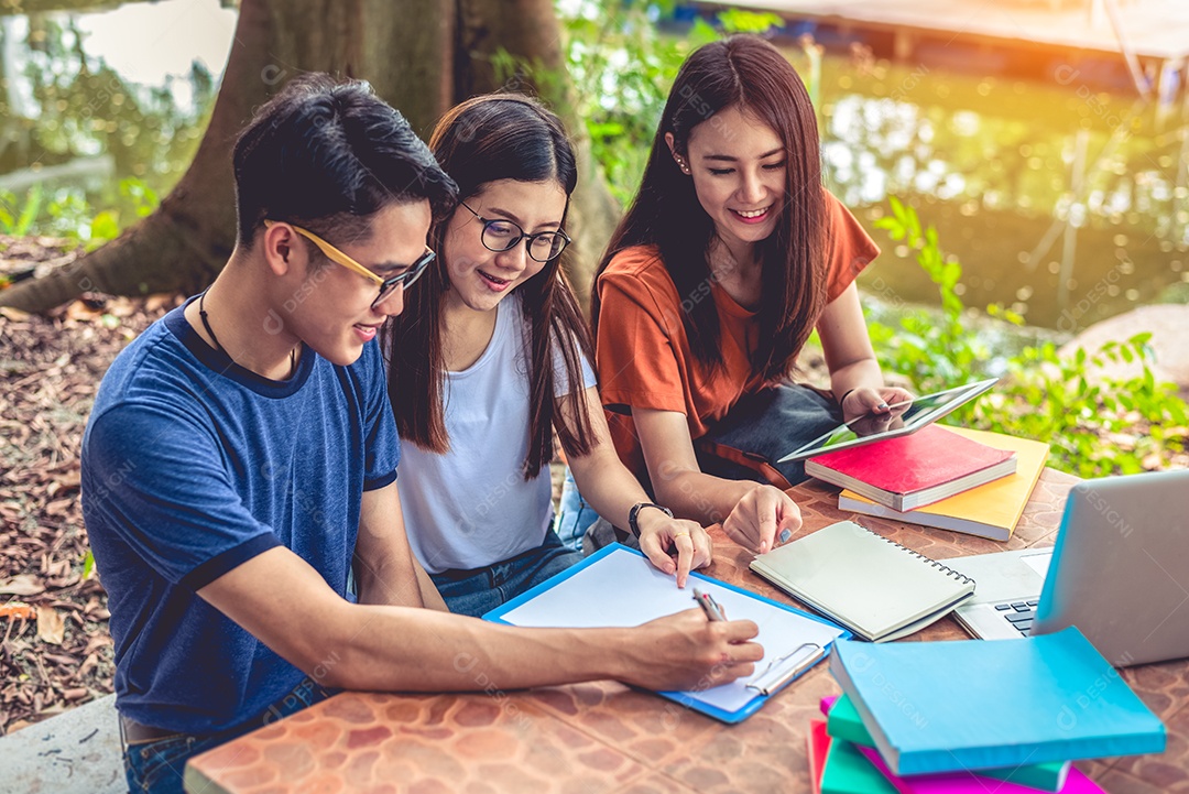 Grupo de estudantes universitários asiáticos lendo livros e aulas particulares.