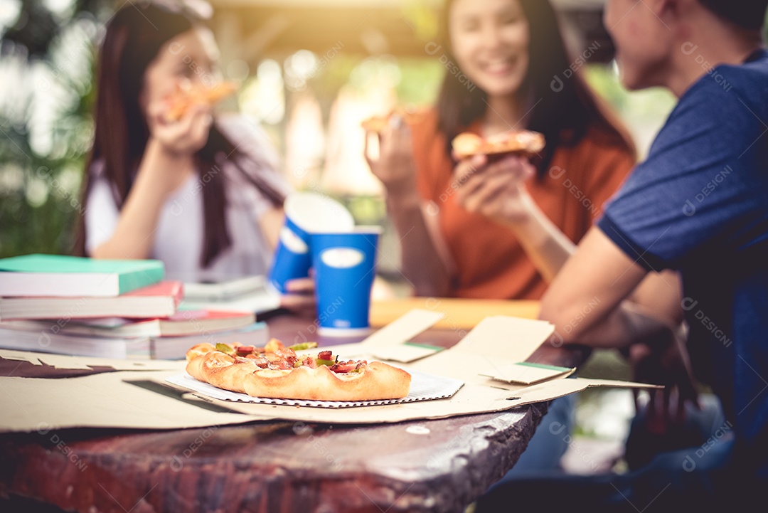 Três asiáticos gostam de comer pizza ao ar livre após aulas particulares.