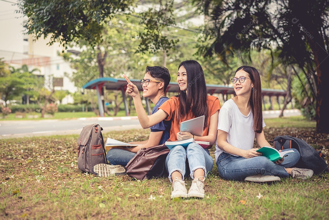 Grupo de estudantes universitários asiáticos lendo livros e aulas particulares.