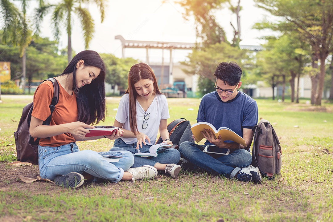Grupo de estudantes universitários asiáticos lendo livros e aulas particulares.
