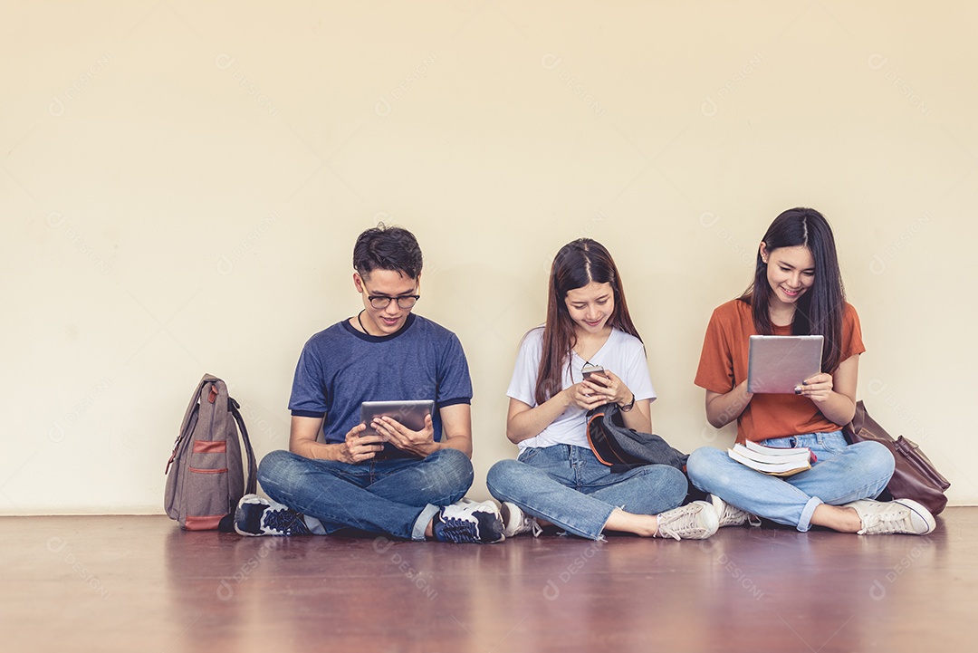 Grupo de estudantes universitários asiáticos usando tablet e celular.