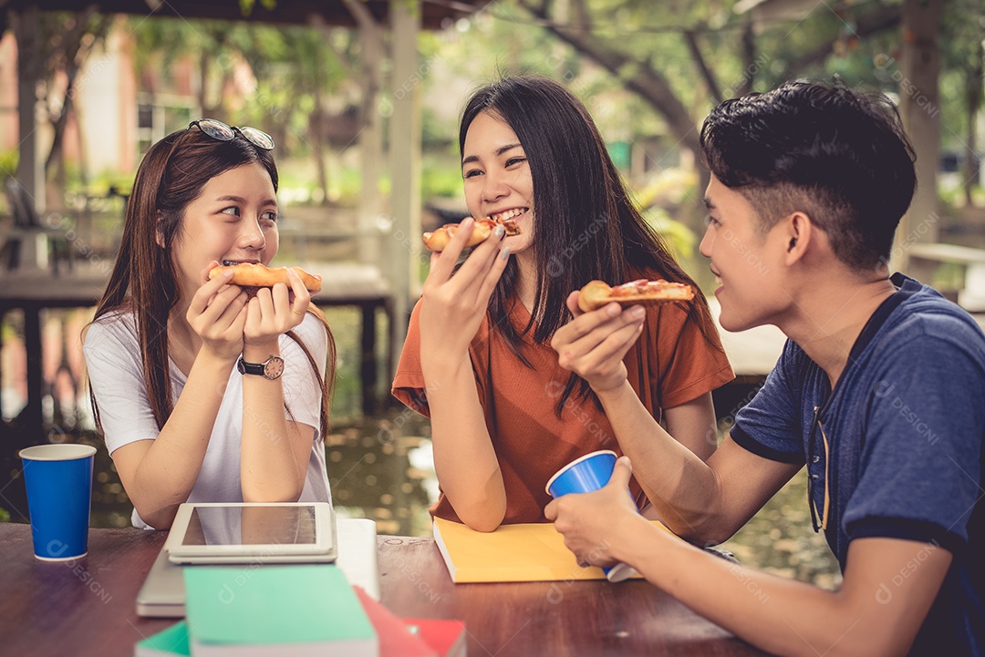 Jovens asiáticos comemorando com pizza na mão. Comida e fritas.