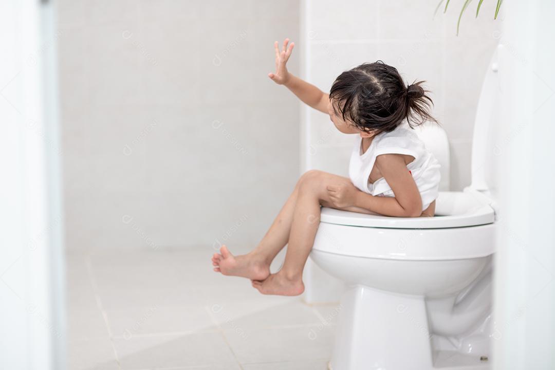 A garotinha está sentada no vaso sanitário sofrendo de constipação ou hemorroida.