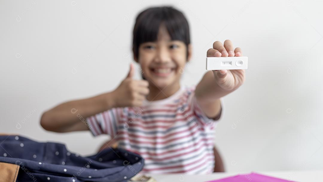 Menina asiática é testada para covid-19 antes da aula.