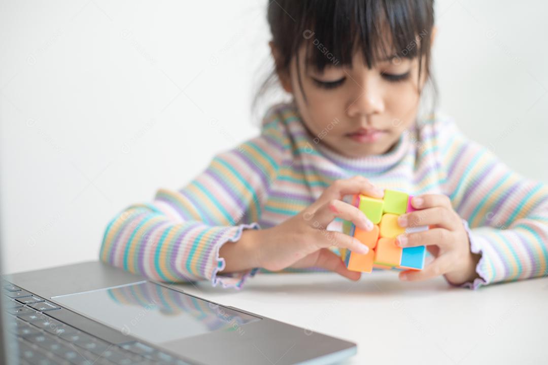 Menina asiática bonitinha segurando o cubo de Rubik nas mãos dela.