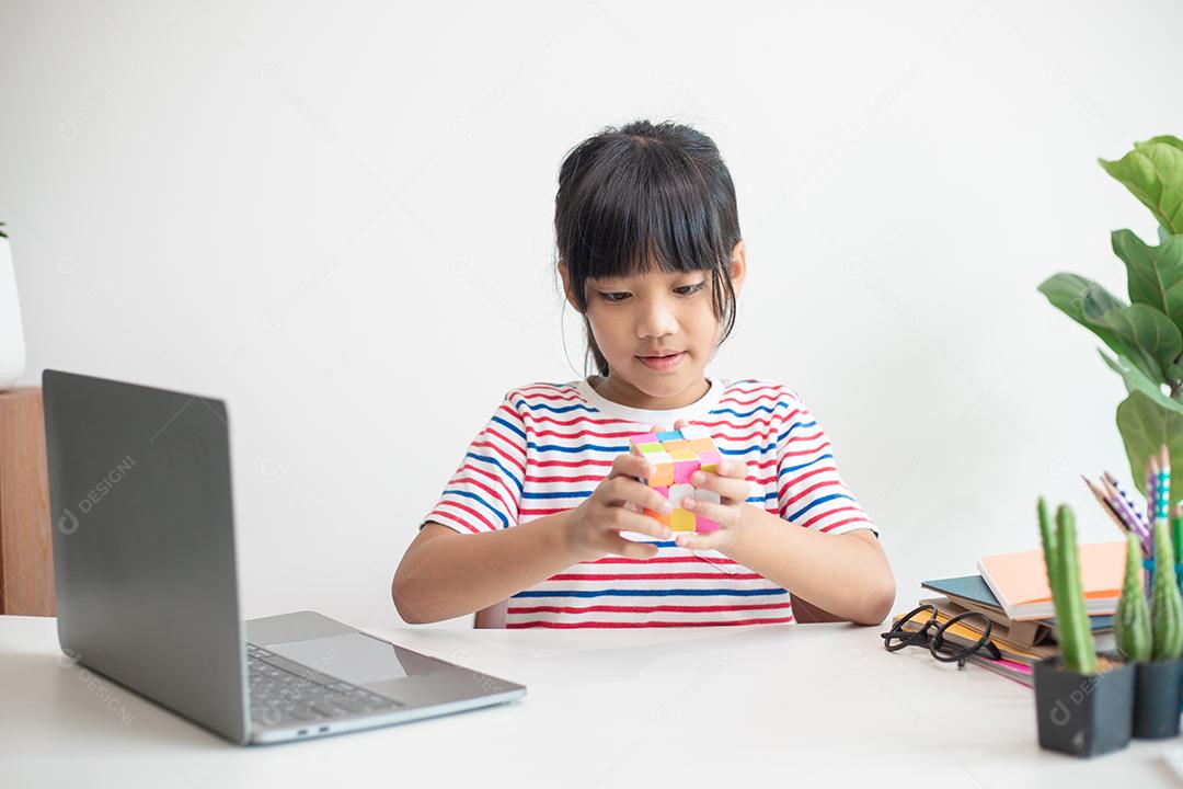 Menina asiática bonitinha segurando o cubo de Rubik nas mãos dela.