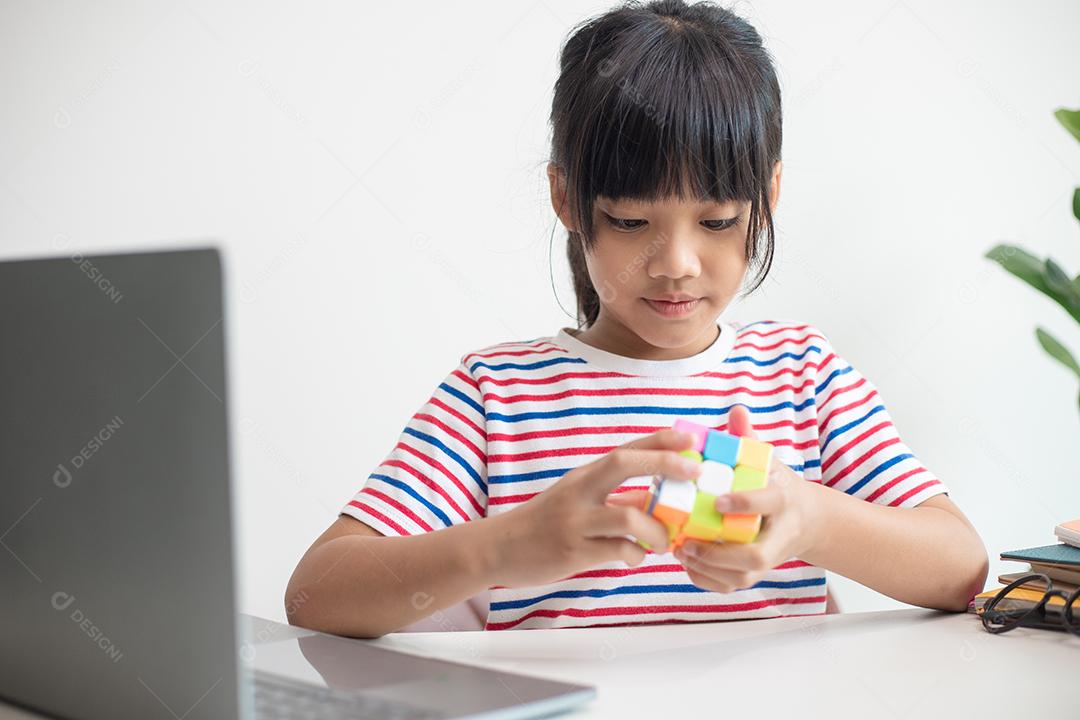 Menina asiática bonitinha segurando o cubo de Rubik nas mãos dela.