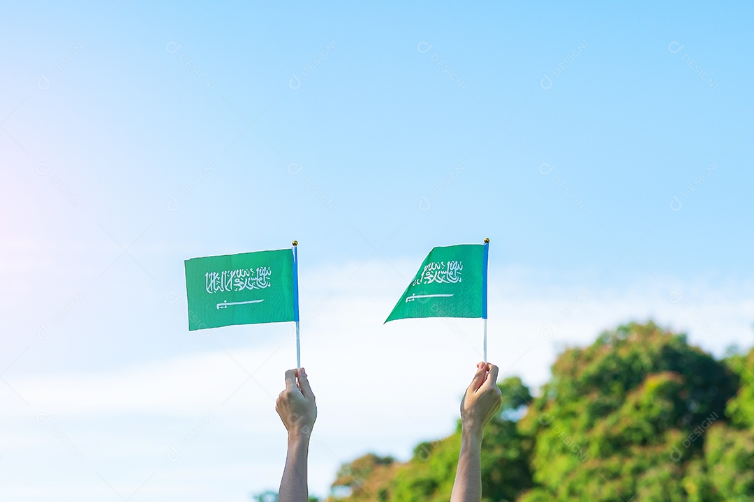 mão segurando a bandeira da Arábia Saudita no fundo do céu azul. Dia nacional da Arábia Saudita de setembro e conceitos de celebração feliz