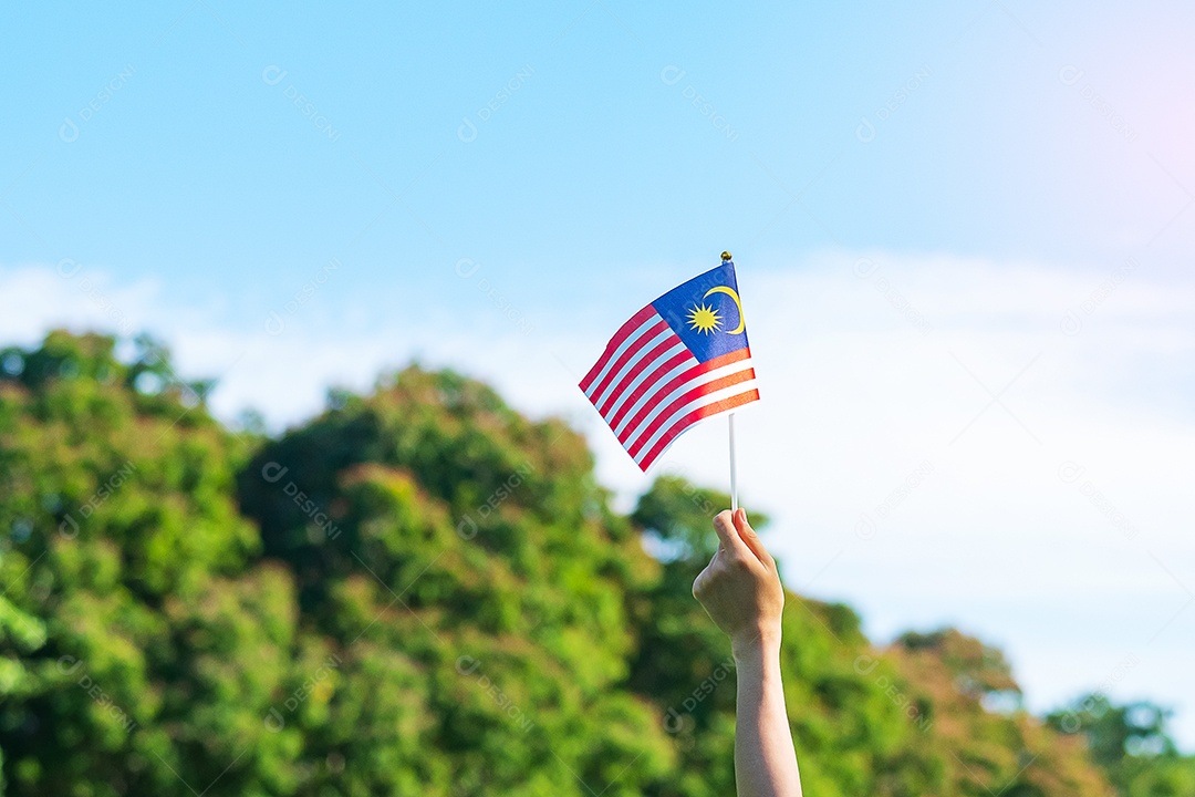 mão segurando a bandeira da Malásia no fundo do céu azul. Dia nacional da Malásia de setembro e dia da independência de agosto