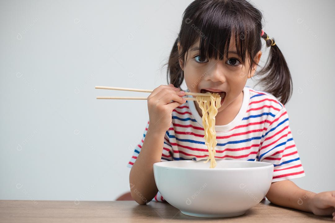 Linda garota asiática comendo deliciosos macarrão instantâneo em casa.
