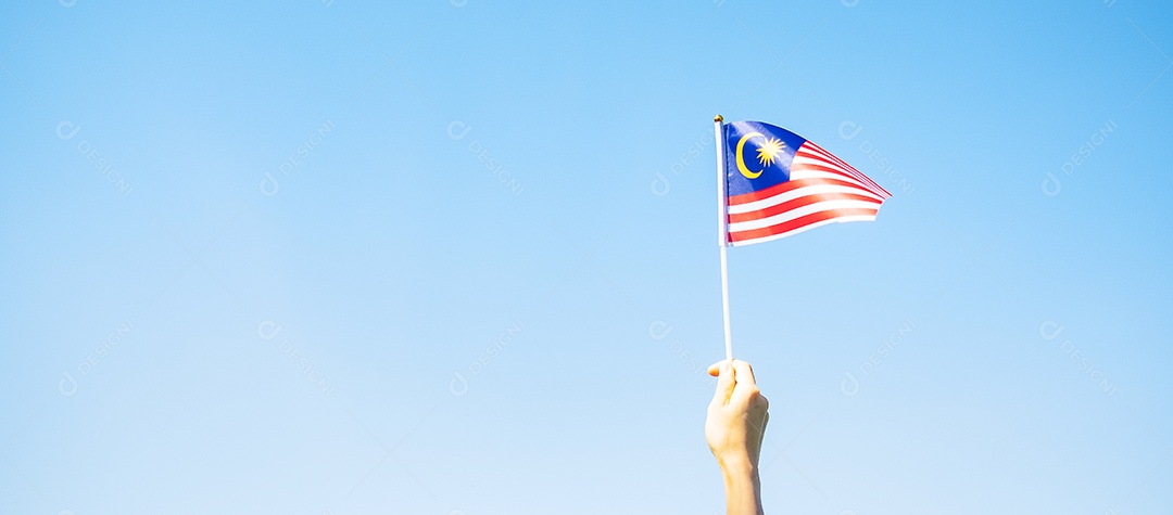 mão segurando a bandeira da Malásia no fundo do céu azul. Dia nacional da Malásia de setembro e dia da independência de agosto