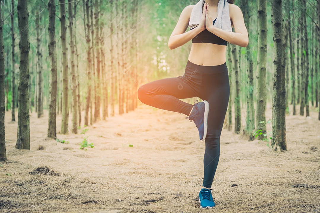 Bela jovem asiática em pé e fazendo ioga na floresta.