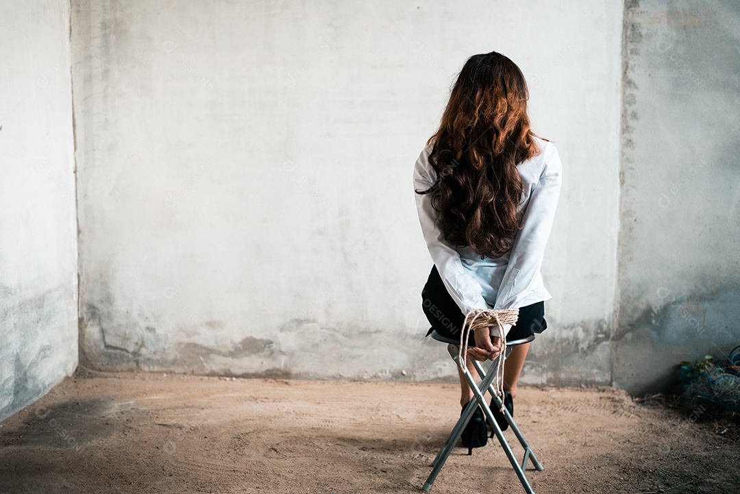 Vista traseira da mulher refém com corda de gravata nas mãos.
