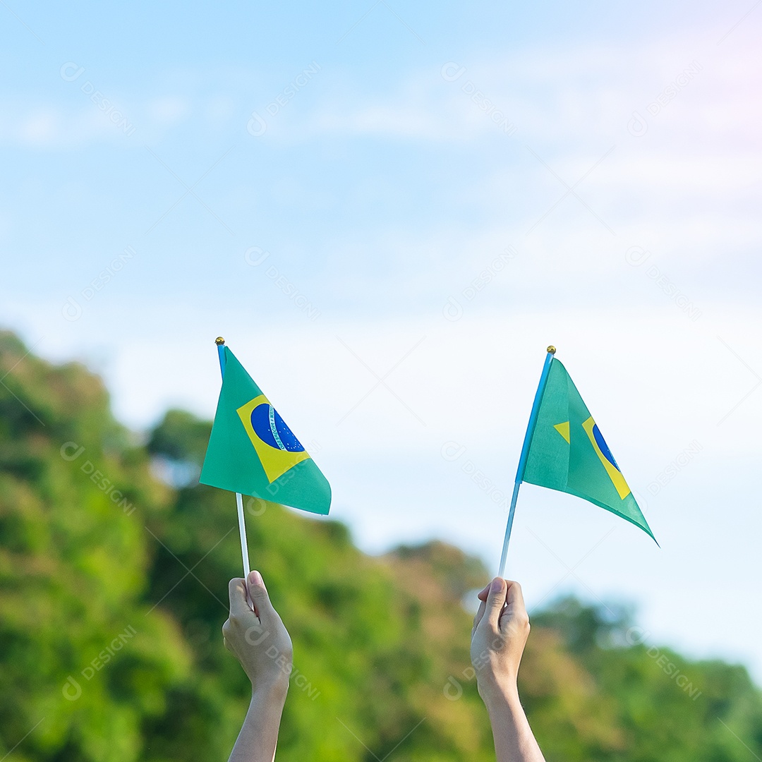 mão segurando a bandeira do Brasil sobre fundo de céu azul. Dia da independência de setembro e conceitos de celebração feliz