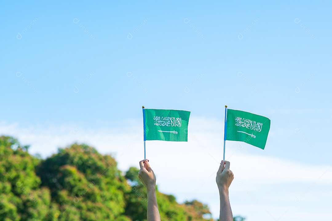 mão segurando a bandeira da Arábia Saudita no fundo do céu azul. Dia nacional da Arábia Saudita de setembro e conceitos de celebração feliz
