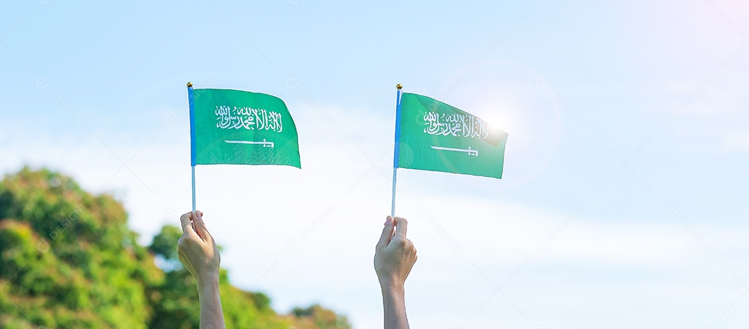 mão segurando a bandeira da Arábia Saudita no fundo do céu azul. Dia nacional da Arábia Saudita de setembro e conceitos de celebração feliz