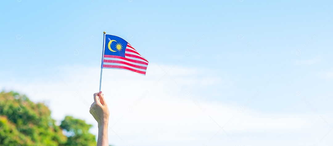 hand holding malaysia flag on blue sky background. Malaysian National Day September and Independence Day August