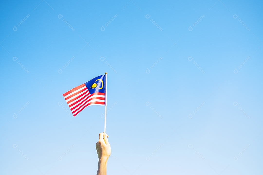 mão segurando a bandeira da Malásia no fundo do céu azul. Dia nacional da Malásia de setembro e dia da independência de agosto