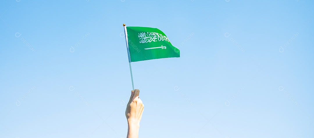 mão segurando a bandeira da Arábia Saudita no fundo do céu azul. Dia nacional da Arábia Saudita de setembro e conceitos de celebração feliz