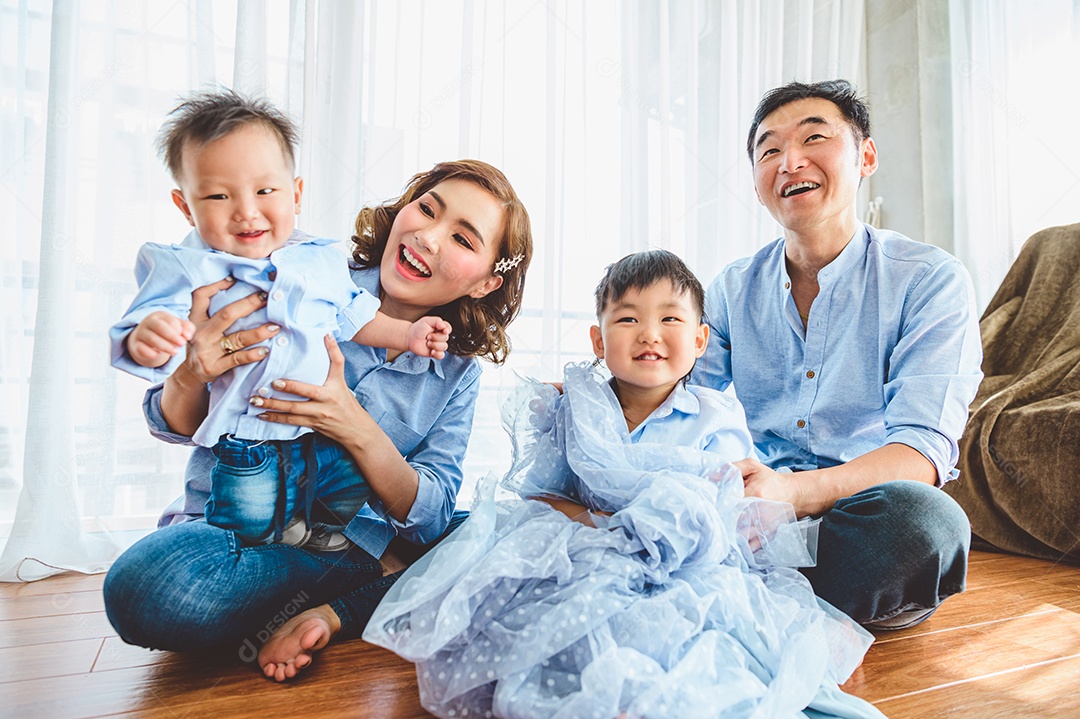 Família asiática feliz sorri e ri juntos na sala de estar em casa. Dois pais e dois filhos filhos.