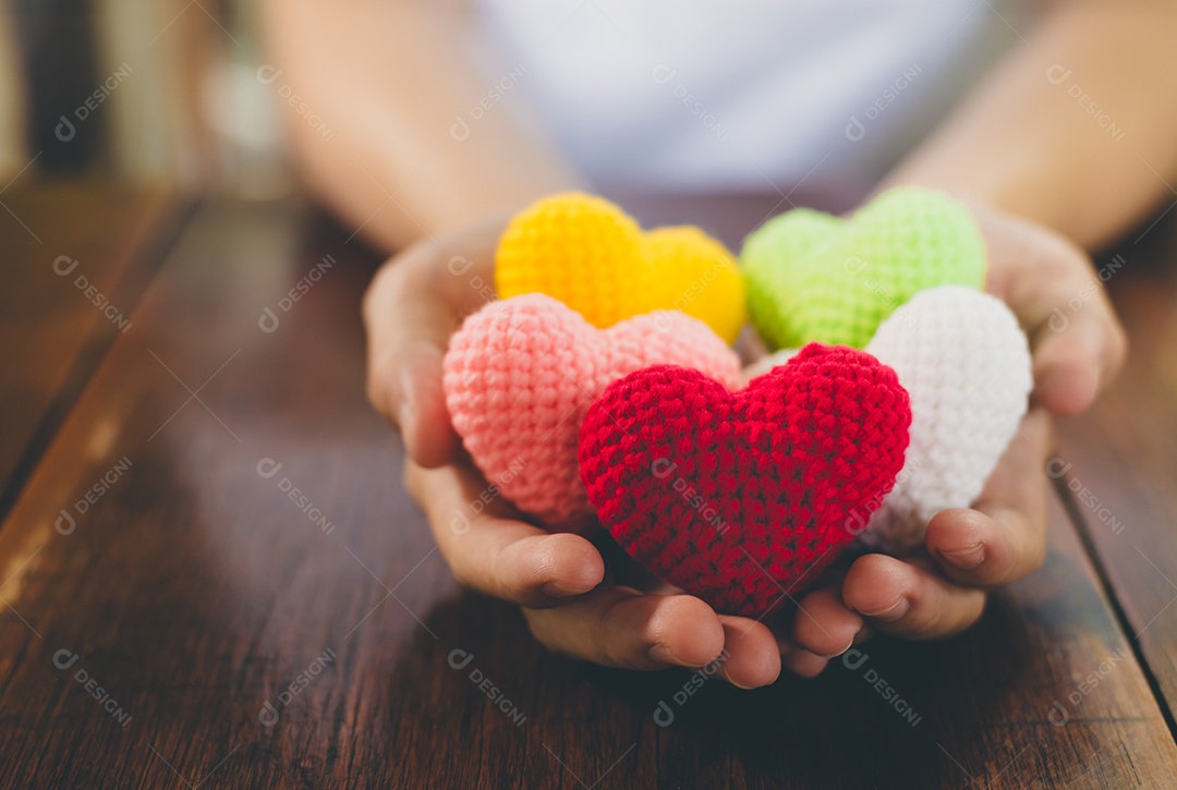 Coração de fio de cores misturadas em dar as mãos. Feche de colorido feito à mão. Doação de coração saudável e conceito de cuidados de saúde.