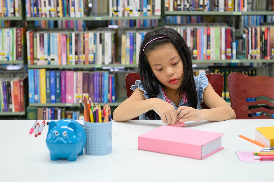 Menina asiática dobrando e criando papel na biblioteca durante a aula de arte. Conceito de educação e atividade.