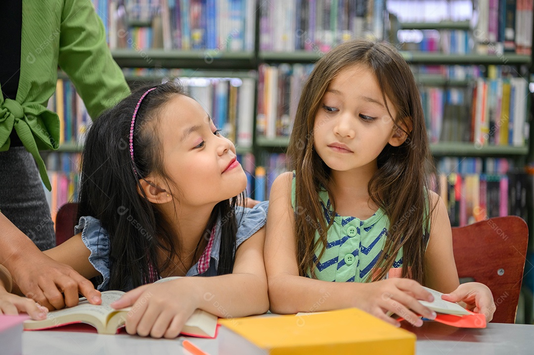 Duas garotas bonitas têm ciúmes uma da outra enquanto leem livros na biblioteca enquanto ensinam o professor.